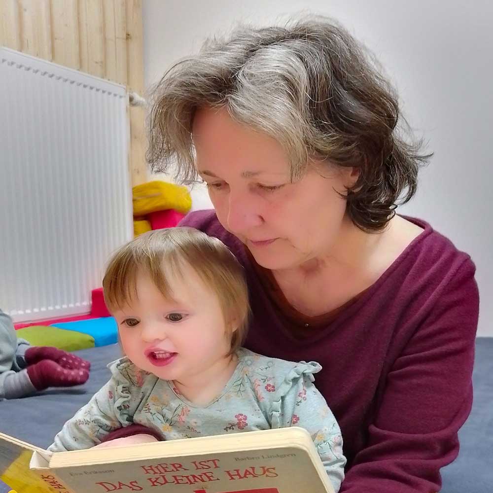 Frauke Gernert liest einem Kind ein Buch vor