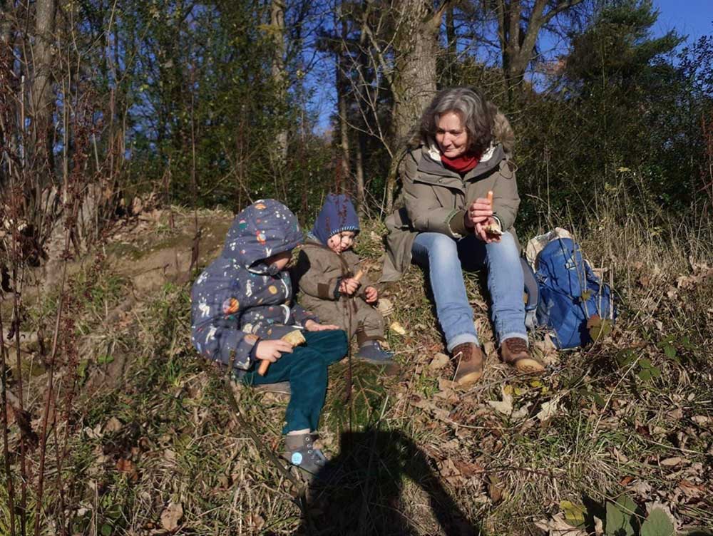 Frauke Gernert sitzt mit Kindern im Wald