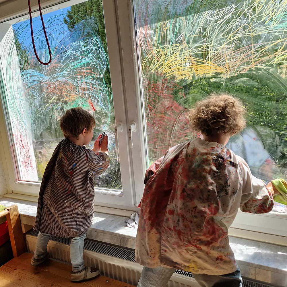 Zwei Kinder malen Fenster an